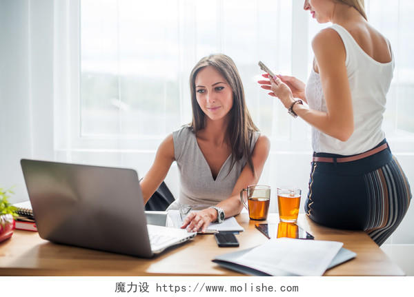 休息时间女子坐在办公桌前看着电脑聊天喝咖啡